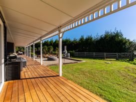 An outdoor deck with furniture and a barbecue at Mangawhai Holiday Home Mangawhai