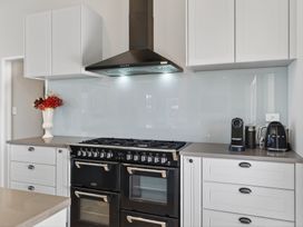 A kitchen with cabinets, stove, oven, and coffee maker at Mangawhai Holiday Home in Mangawhai