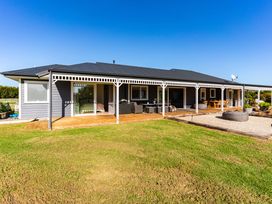 A house with a deck and outdoor seating at Mangawhai Holiday Home Mangawhai