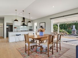 A kitchen with dining table and sliding door to outdoor area at Mangawhai Holiday Home in Mangawhai