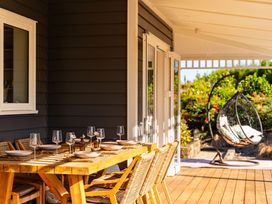 An outdoor seating area with a dining table and chairs at Mangawhai Holiday Home in Mangawhai