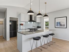 A kitchen with island, stools, and appliances at Mangawhai Holiday Home in Mangawhai