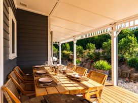 An outdoor dining area with a wooden table and chairs at Mangawhai Holiday Home in Mangawhai