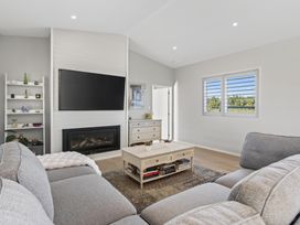 A living room with a sofa, television, and coffee table at Mangawhai Holiday Home in Mangawhai
