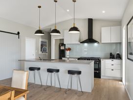 A kitchen with an island and stools at Mangawhai Holiday Home in Mangawhai