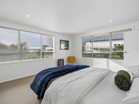 A bedroom with a bed and windows at Martinborough Holiday Home Martinborough