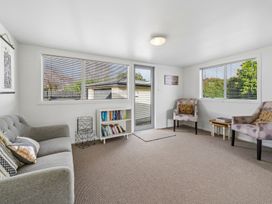 A snug room with a sofa and bookshelf at Martinborough Holiday Home Martinborough