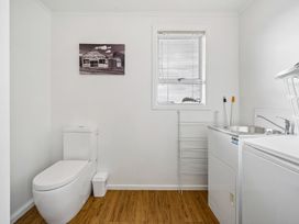 A bathroom with a toilet, sink, and laundry machine at Martinborough Holiday Home, Martinborough