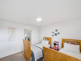 A bedroom with two beds and a chair at Martinborough Holiday Home in Martinborough