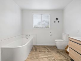 A bathroom featuring a bathtub, toilet, and drawer unit at Martinborough Holiday Home in Martinborough