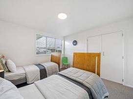 A bedroom with beds and a chair at Martinborough Holiday Home, Martinborough