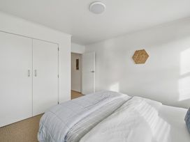 A bedroom with a bed, closet, and wall art at Martinborough Holiday Home in Martinborough
