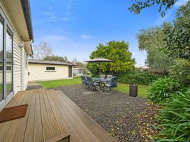 A garden with a table and chairs under an umbrella at Martinborough Holiday Home Martinborough