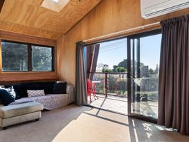 A living room with a sofa and balcony access at Roberts Retreat - Auckland Holiday Home in Laingholm