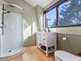 A bathroom with a shower, cabinet, sink, and toilet at Roberts Retreat - Auckland Holiday Home Laingholm
