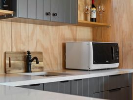 A kitchen with a microwave and sink at Roberts Retreat - Auckland Holiday Home in Laingholm