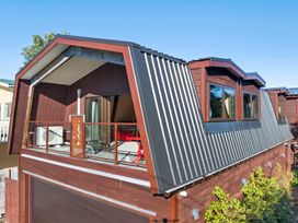 A house with a sloped roof and balcony at Roberts Retreat - Auckland Holiday Home in Laingholm