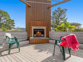 An outdoor area with a fireplace and chairs at Ocean Breeze Family Haven - Pauanui