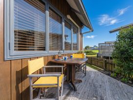An outdoor terrace with a table and chairs at Ocean Breeze Family Haven - Pauanui