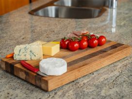 A cutting board with cheese, tomatoes, and ham in a kitchen setting at Ocean Breeze Family Haven - Pauanui