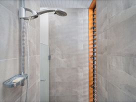A shower with a wall and glass door at Ocean Breeze Family Haven - Pauanui