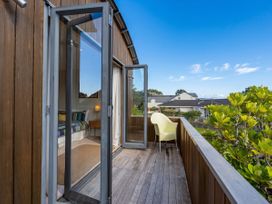 A balcony with a chair overlooking a garden at Ocean Breeze Family Haven - Pauanui