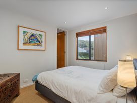 A bedroom with a bed and lamp at Ocean Breeze Family Haven - Pauanui