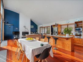 A living room with a dining table and kitchen island at Ocean Breeze Family Haven - Pauanui