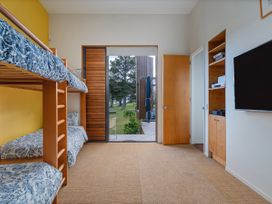 A bedroom with bunk beds and a television at Ocean Breeze Family Haven - Pauanui