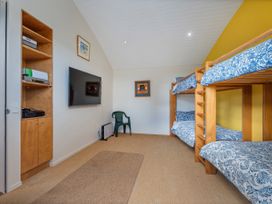 A bedroom with bunk beds and a television at Ocean Breeze Family Haven - Pauanui