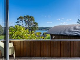 A view from a balcony overlooking a lake and trees at Ocean Breeze Family Haven - Pauanui