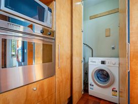 A laundry room with a washing machine and built-in appliances at Ocean Breeze Family Haven - Pauanui