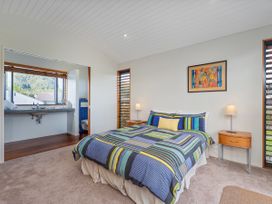 A bedroom with a bed and adjoining bathroom at Ocean Breeze Family Haven - Pauanui