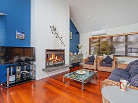 A living room with a fireplace and seating area at Ocean Breeze Family Haven - Pauanui