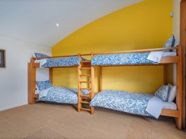 A bedroom with bunk beds and a ladder at Ocean Breeze Family Haven - Pauanui