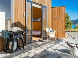 An outdoor deck with a grill and chair at Ocean Breeze Family Haven - Pauanui