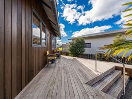 A deck with wooden stairs and outdoor furniture at Ocean Breeze Family Haven - Pauanui