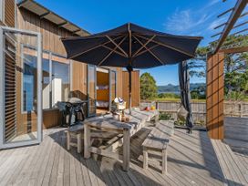 An outdoor seating area with a table and umbrella at Ocean Breeze Family Haven - Pauanui