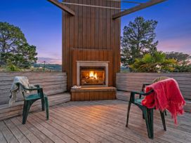 An outdoor living area with a fireplace and chairs at Ocean Breeze Family Haven - Pauanui