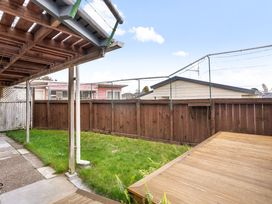 A garden with grass and a wooden deck at Tauranga Holiday Home in Tauranga