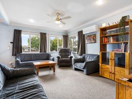 A living room with sofas, a coffee table, and a bookshelf at Tauranga Holiday Home in Tauranga