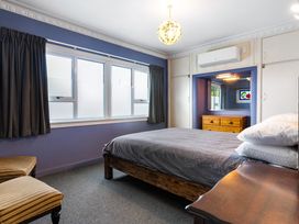 A bedroom with a bed and windows at Tauranga Holiday Home in Tauranga