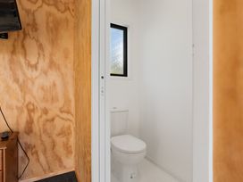 A bathroom with a toilet and a window at Panorama View Retreat - Bachcare Holiday Home Pauanui