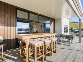An outdoor patio with a bar table and stools at Panorama View Retreat - Bachcare Holiday Home, Pauanui