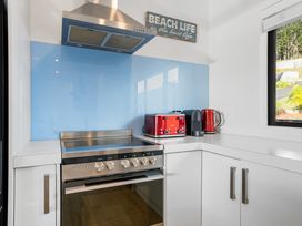A kitchen with a stove and red kettle at Panorama View Retreat - Bachcare Holiday Home Pauanui
