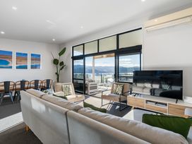 A living room with sofa and dining area at Panorama View Retreat - Bachcare Holiday Home, Pauanui