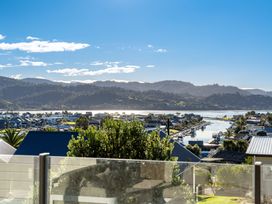 A view of water and houses with mountains in the background at Panorama View Retreat - Bachcare Holiday Home, Pauanui