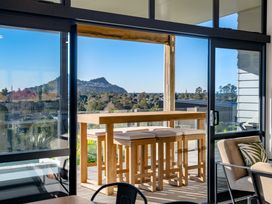 An outdoor area with a wooden table and bar stools at Panorama View Retreat - Bachcare Holiday Home Pauanui