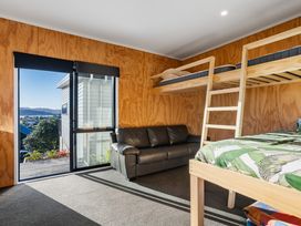 A bedroom with a bunk bed and sofa at Panorama View Retreat - Bachcare Holiday Home Pauanui