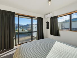 A bedroom with a checked bedspread and large windows at Belle Vue in Akaroa